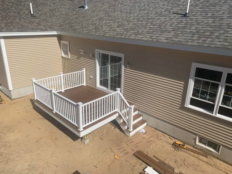 New composite deck with white vinyl railings and stairs on a Maine home