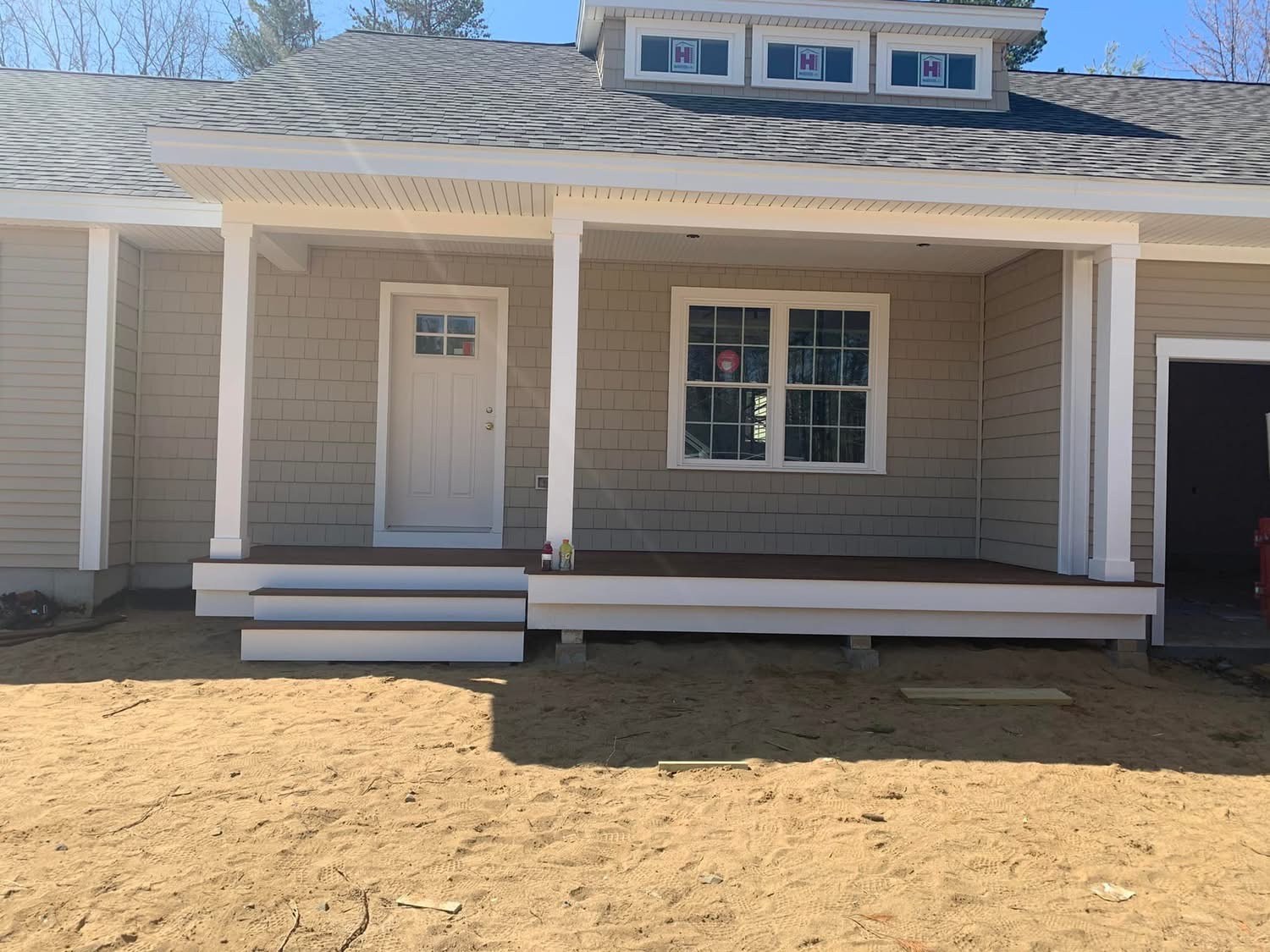 New covered farmhouse porch with composite decking and white columns