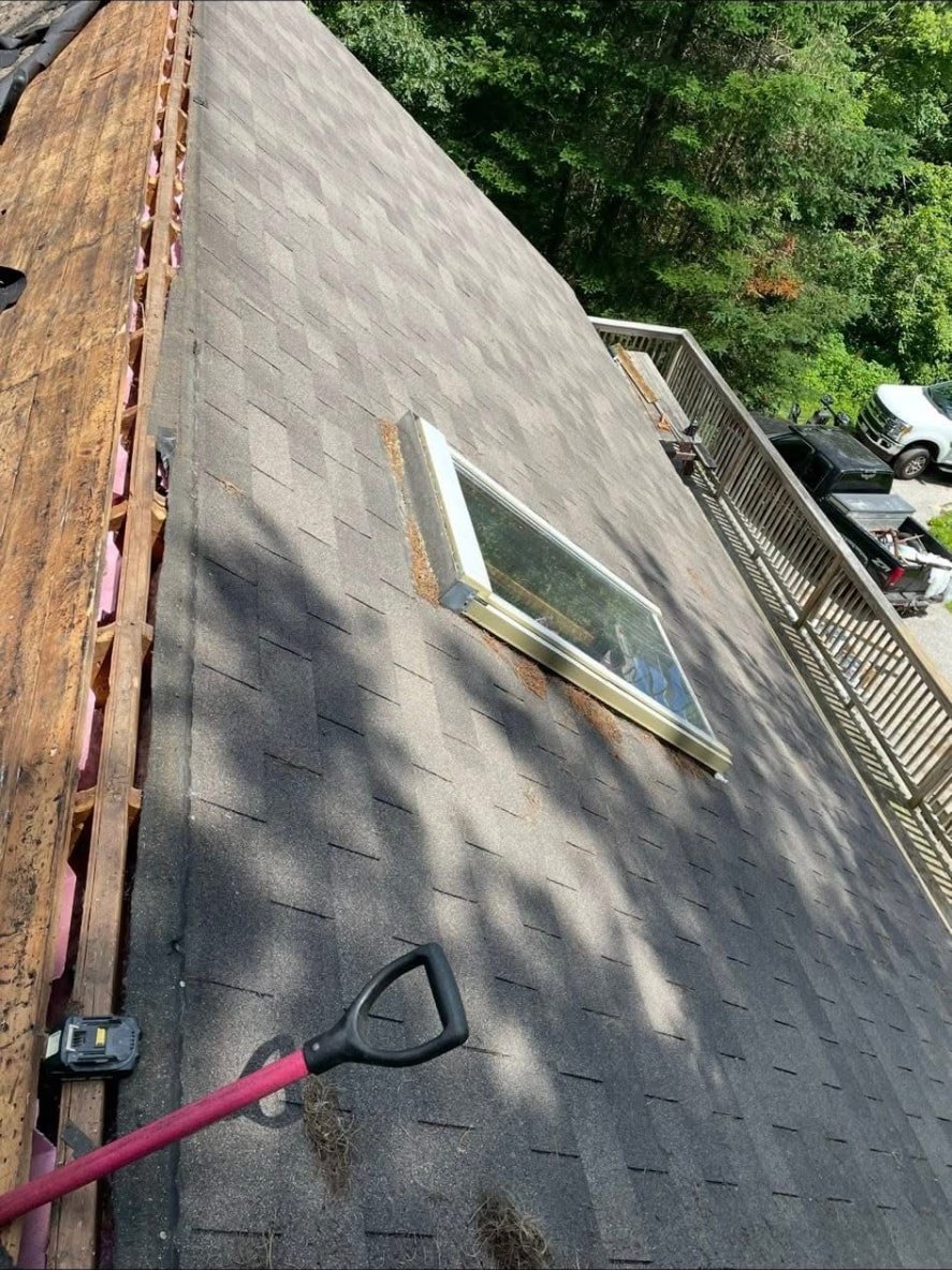 Roof tear-off in progress around a skylight on a Maine home